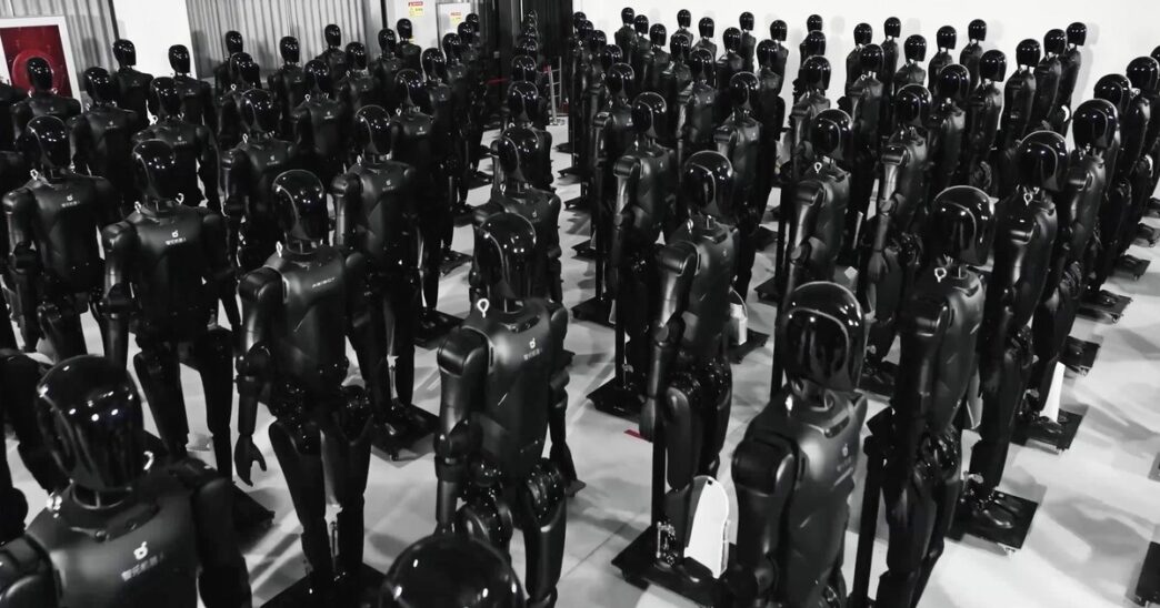 Rows of black AgiBot Expedition A2 humanoid robots standing on stands inside an AgiBot facility
