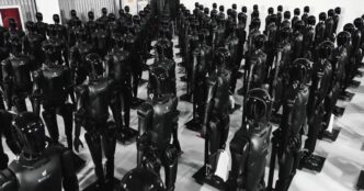 Rows of black AgiBot Expedition A2 humanoid robots standing on stands inside an AgiBot facility