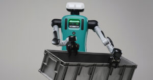Agility Robotics Digit humanoid robot with a teal torso carrying a grey plastic tote against a plain grey background