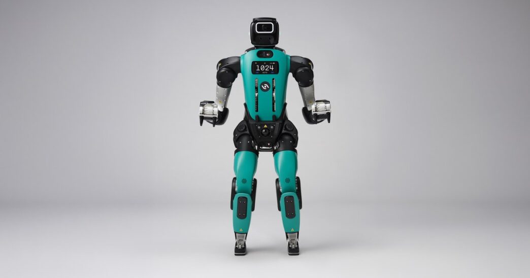 Agility Robotics Digit 5 humanoid robot standing front-facing in a gray studio, teal torso and black head with chest display