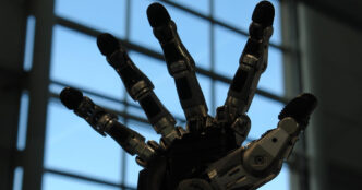 Black Schunk SVH five-finger robotic hand with its fingers spread, photographed against a bright window