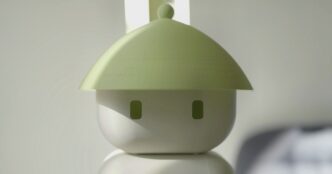 Close-up of the Flourish 1 home robot's round white head with two small rectangular eyes under a wide pale-green conical hat