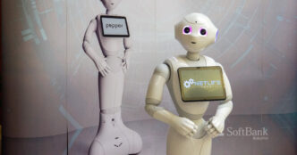 White Pepper humanoid robot by SoftBank Robotics with a tablet screen on its chest, standing in front of a second Pepper