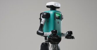Agility Robotics Digit humanoid with a teal torso and white head unit, arms bent forward, against a grey studio backdrop