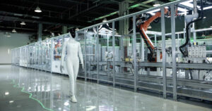 White XPENG IRON humanoid robot with a black face walking on a polished floor beside a glass-walled automated production line with orange industrial robot arms