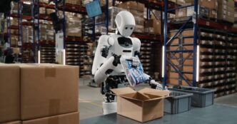 Apptronik Apollo humanoid robot packing an item into a cardboard box in a warehouse with tall shelving