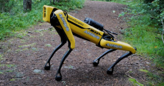 Boston Dynamics Spot quadruped robot walking on a dirt path through a forest