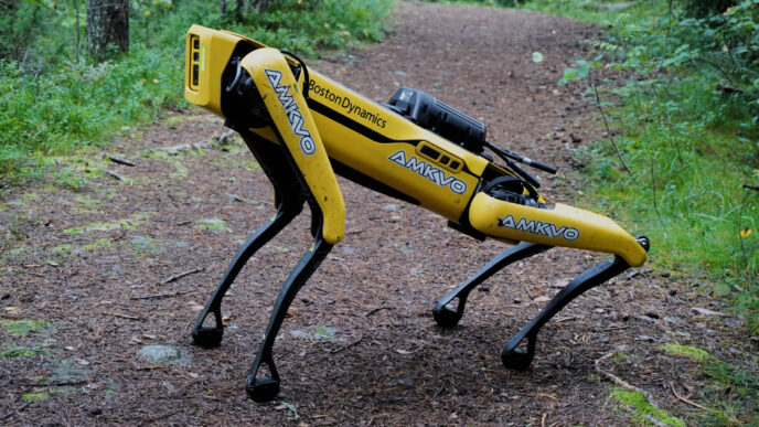 Boston Dynamics Spot quadruped robot walking on a dirt path through a forest