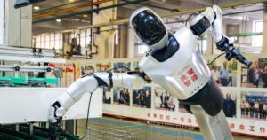 Humanoid robot placing an auto part at a workstation on a Hangzhou auto-parts production line, photographed October 13, 2026
