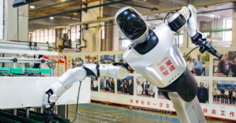 Humanoid robot placing an auto part at a workstation on a Hangzhou auto-parts production line, photographed October 13, 2026