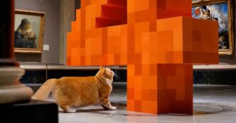 An orange cat walks through a marble art gallery toward a giant orange pixel-block sculpture of the number 4, a still from Mistral's Large 4 launch video