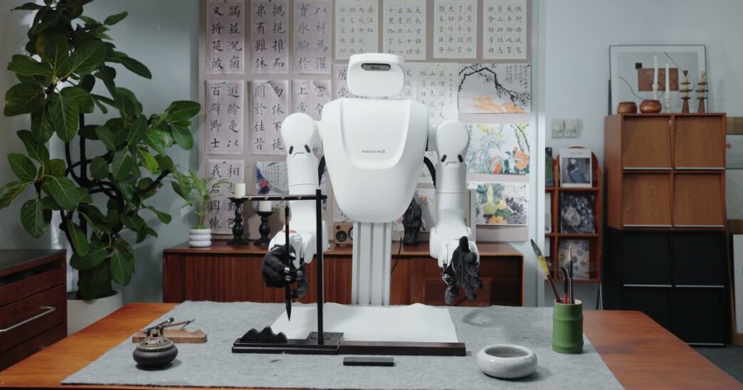 Nature Will dual-arm robot with dexterous hands holding a calligraphy brush at a desk in the Natura-1 demo