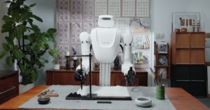 Nature Will dual-arm robot with dexterous hands holding a calligraphy brush at a desk in the Natura-1 demo
