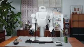 Nature Will dual-arm robot with dexterous hands holding a calligraphy brush at a desk in the Natura-1 demo