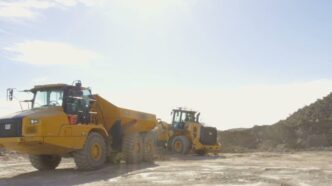 Yellow CAT wheel loader and articulated dump truck on a dusty Utah worksite, from Physical Intelligence's Actor partner demo for the Pi API beta