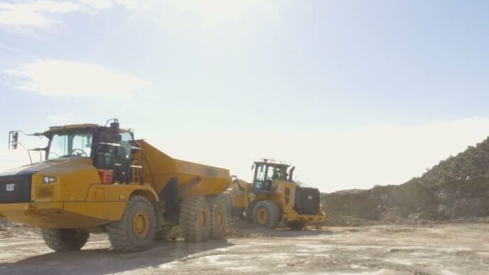 Yellow CAT wheel loader and articulated dump truck on a dusty Utah worksite, from Physical Intelligence's Actor partner demo for the Pi API beta