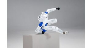 RoboParty RP1 white-and-blue humanoid robot vaulting over a gray pedestal in a studio, head and blue ROMOMO joint modules visible
