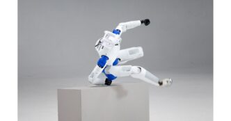 RoboParty RP1 white-and-blue humanoid robot vaulting over a gray pedestal in a studio, head and blue ROMOMO joint modules visible