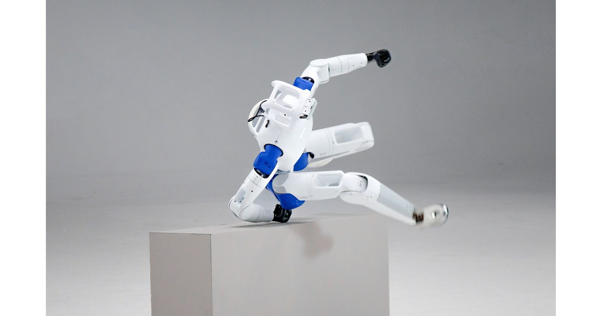 RoboParty RP1 white-and-blue humanoid robot vaulting over a gray pedestal in a studio, head and blue ROMOMO joint modules visible