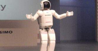 Honda ASIMO humanoid robot standing on a stage with its arms spread wide