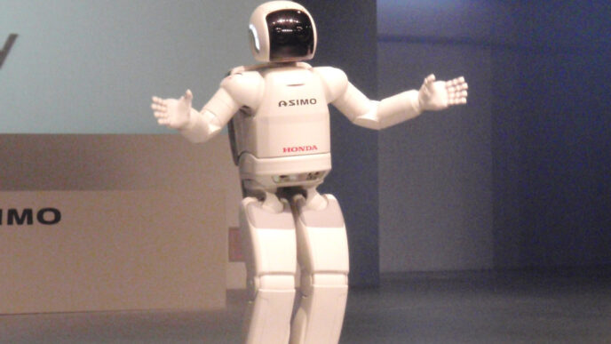 Honda ASIMO humanoid robot standing on a stage with its arms spread wide