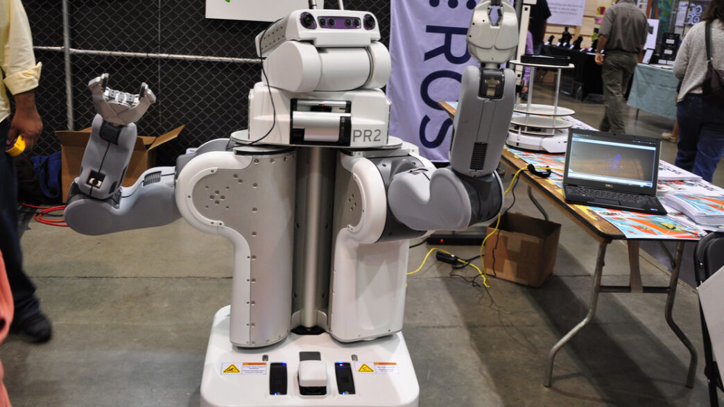 Willow Garage PR2 research robot, a white two-armed mobile robot with a camera-equipped head, shown at an exhibition