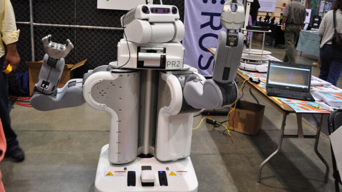 Willow Garage PR2 research robot, a white two-armed mobile robot with a camera-equipped head, shown at an exhibition