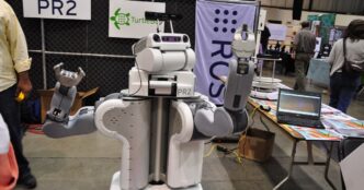 Willow Garage PR2 research robot, a white two-armed mobile robot with a camera-equipped head, shown at an exhibition