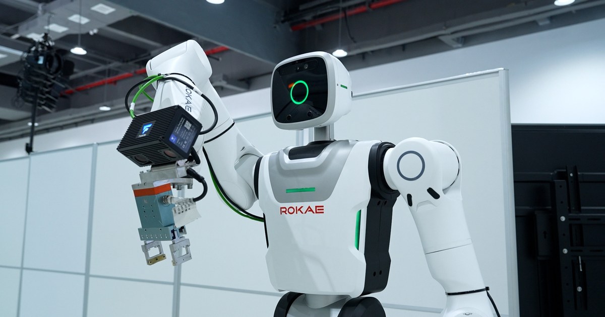 A white ROKAE-branded humanoid robot with a green face display working at an assembly station inside Schaeffler's Taicang factory