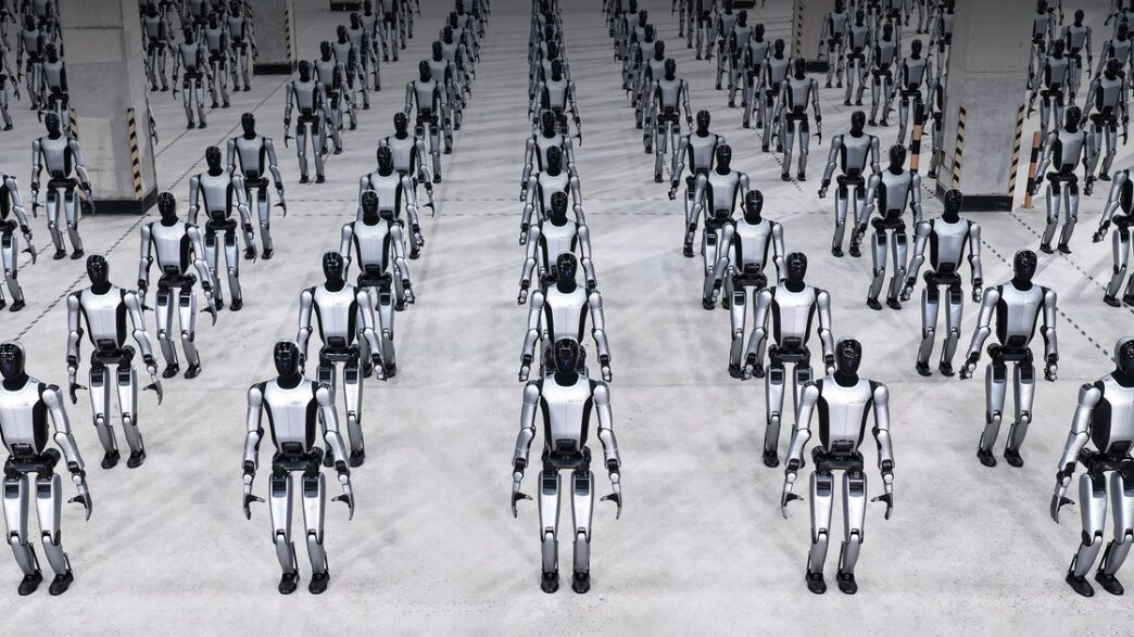 Rows of silver-and-black UBTech Walker S2 humanoid robots standing in formation on a grey concrete floor in a large hall
