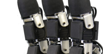 Close-up of robot fingers with black rounded fingertips and black uSkin tactile sensor pads above silver joints, against a white background