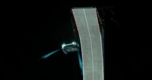 White Tesla Roadster in midair beside a curled concrete ramp at night, firing blue cold-gas thruster plumes during Tesla's October 15, 2026 reveal