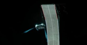 White Tesla Roadster in midair beside a curled concrete ramp at night, firing blue cold-gas thruster plumes during Tesla's October 15, 2026 reveal