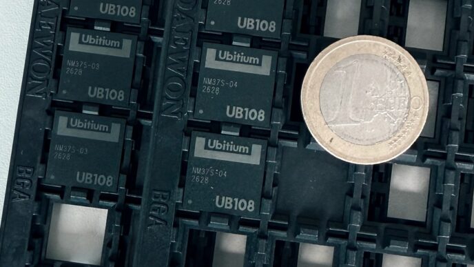 Four black Ubitium UB108 processor chips in a JEDEC tray beside a one-euro coin for scale