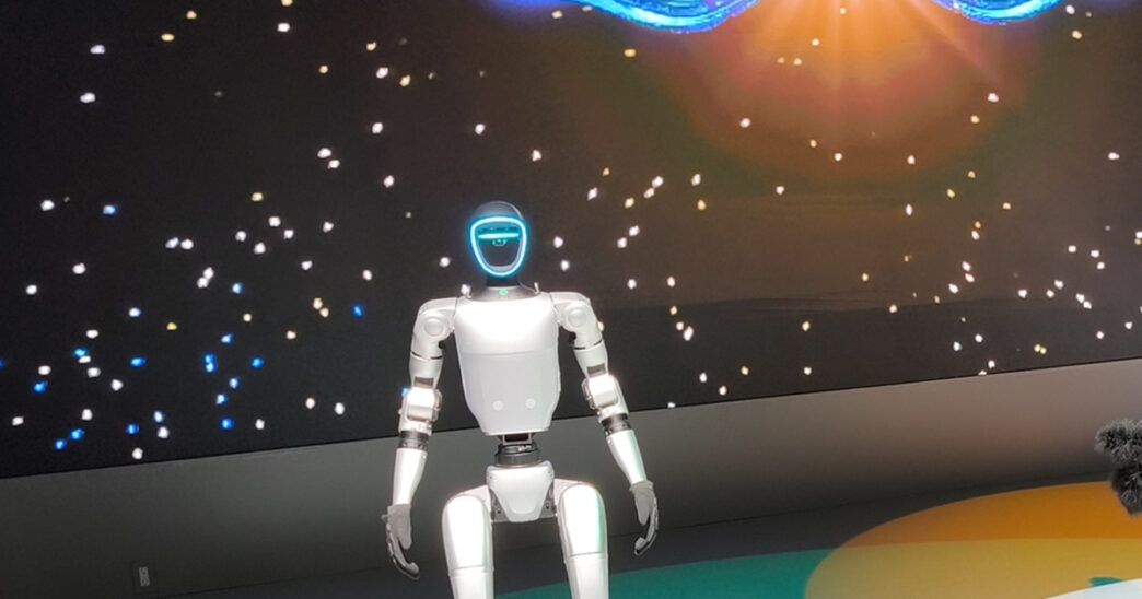 Unitree G1 humanoid robot standing on a lit circular stage at the Japan Mobility Show 2025